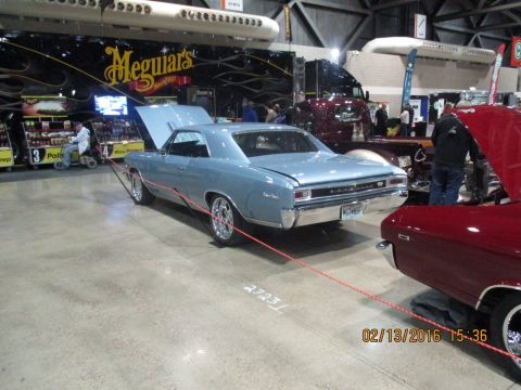 2004 Ford Crown Victoria - A light blue 1966 Chevrolet Chevelle coupe is displayed indoors with its hood open, alongside other vehicles.