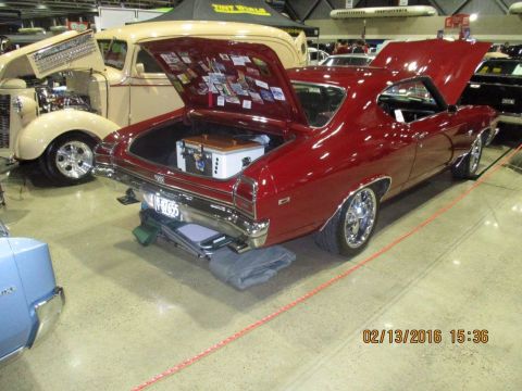 2004 Ford Crown Victoria - A red 1969 Chevrolet Chevelle SS is displayed with its trunk open, revealing a cooler and various stickers inside.