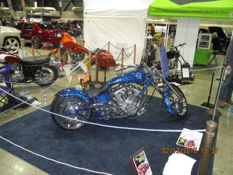 2004 Ford Crown Victoria - A custom chopper motorcycle with intricate blue graphics is showcased at an indoor event, with other vehicles in the background.