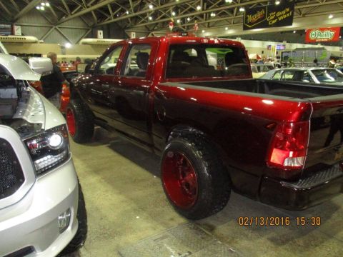 2004 Ford Crown Victoria - A red pickup truck with custom red wheels is parked indoors next to a white vehicle.