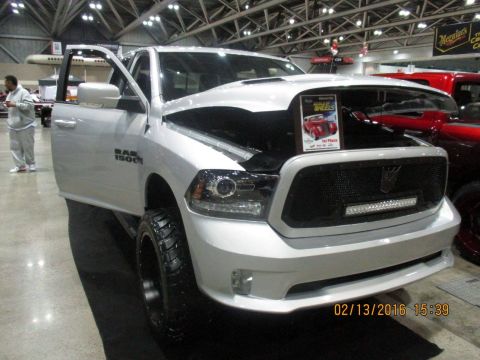 2004 Ford Crown Victoria - A white Ram 1500 pickup truck is displayed with its hood open, showing a trophy for 'World On Wheels'.