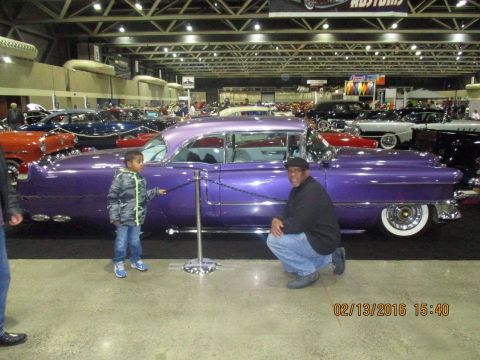 2004 Ford Crown Victoria - A purple classic car is displayed indoors with other vehicles and attendees.