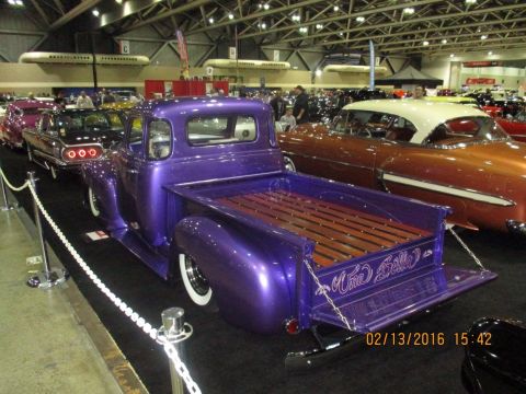 2004 Ford Crown Victoria - A custom purple pickup truck with a wooden bed is displayed at a car show, alongside other vehicles.
