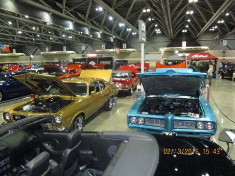 2004 Ford Crown Victoria - Multiple classic cars are displayed indoors at a car show event.
