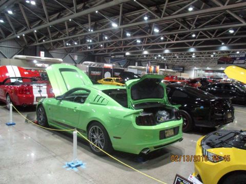 2004 Ford Crown Victoria - A lime green Ford Mustang is displayed with its hood and trunk open at an indoor car show.