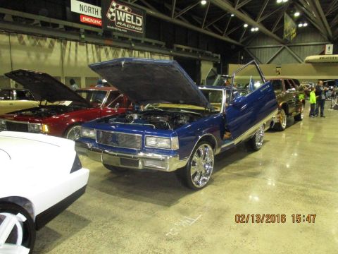 2004 Ford Crown Victoria - Customized blue sedan with gullwing doors on display at an indoor car show.
