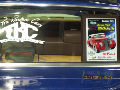 2004 Ford Crown Victoria - A sticker for 'Tru Kustom Cars' and a 'World of Wheels 2016' trophy are visible inside a blue vehicle.
