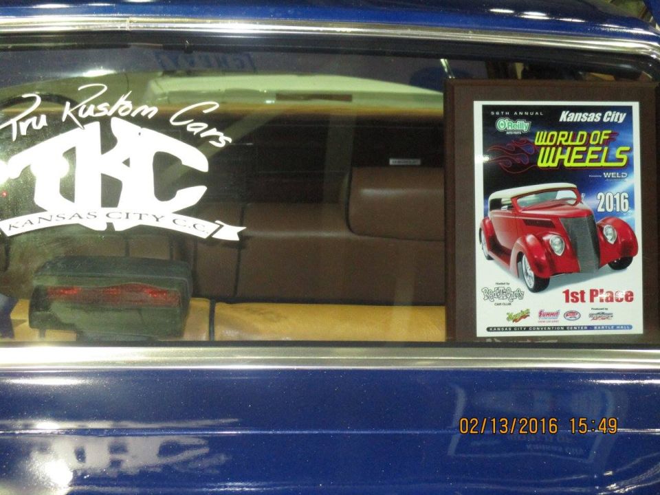 Interior view of a blue car with a 'Tru Kustom Cars' sticker and a 'World of Wheels 2016' trophy