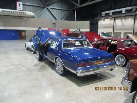 2004 Ford Crown Victoria - Blue sedan with custom doors open at an indoor car show.
