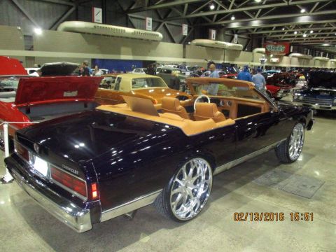 2004 Ford Crown Victoria - A custom convertible with a tan interior and chrome wheels is displayed at an indoor event.