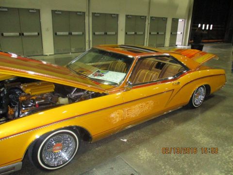 2004 Ford Crown Victoria - A customized classic car with its hood open is displayed indoors, a bright yellow paint job and intricate pinstriping.