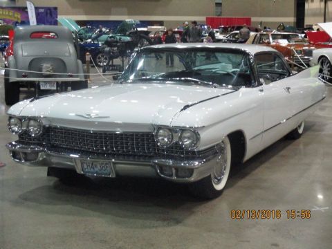 2004 Ford Crown Victoria - White 1959 Cadillac Coupe de Ville on display at a car show.