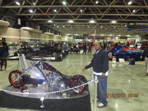 2004 Ford Crown Victoria - A custom motorcycle is displayed at an indoor event, with a man standing next to it.