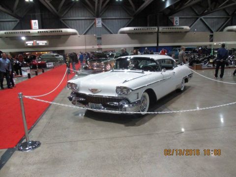 2004 Ford Crown Victoria - White 1958 Cadillac Eldorado Brougham on display at an indoor car show.