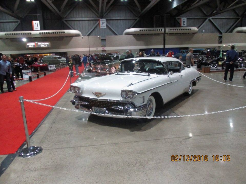 White 1958 Cadillac Eldorado Brougham parked indoors with a red carpet nearby