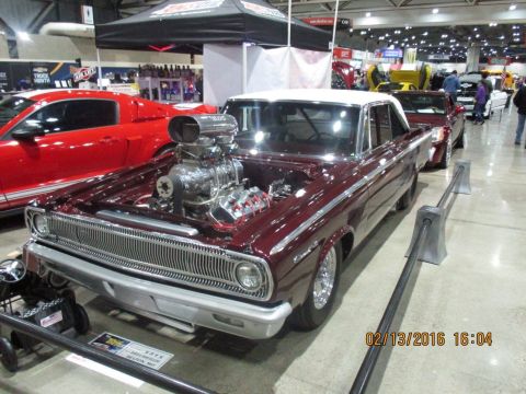 2004 Ford Crown Victoria - A heavily modified vintage car is displayed indoors, a prominent supercharger and a white roof.