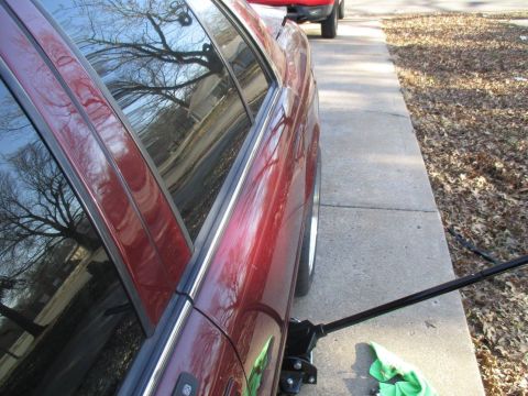 2004 Ford Crown Victoria - A red sedan is being lifted by a jack, with another vehicle visible in the distance.