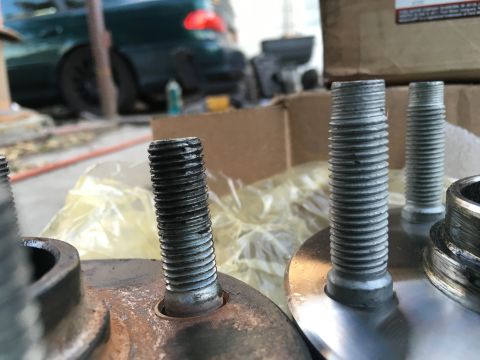 2003 Ford Taurus - Close-up of wheel studs, with a green vehicle visible in the blurred background.