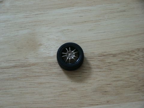1998 Mercury Sable - A single wheel with a silver multi-spoke rim and black tire is shown against a wooden background.