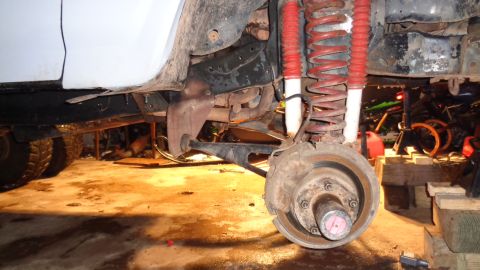 1985 Ford Bronco - The front suspension and brake system of a vehicle is shown in detail, undergoing maintenance or awaiting maintenance.