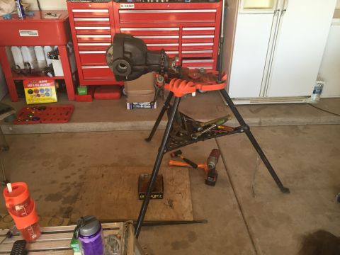 1991 Ford Bronco - A vehicle differential is held in a vise stand in a garage setting, surrounded by tools and storage cabinets.
