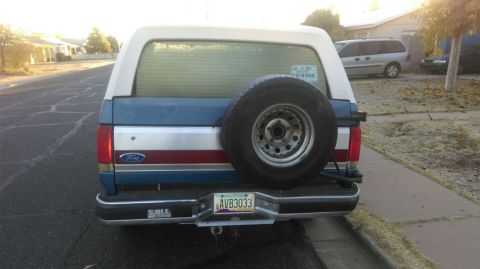 1991 Ford Bronco - This 1991 Ford Bronco features a blue and white exterior with a spare tire mounted on the rear tailgate.