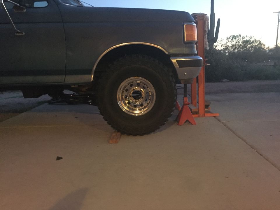 1991 Ford Bronco side view, dark color, large tires on jack stands