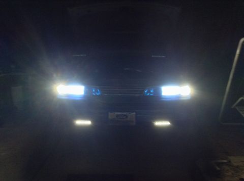 1994 Ford Crown Victoria - The front of a 1994 Ford Crown Victoria is illuminated by its headlights.