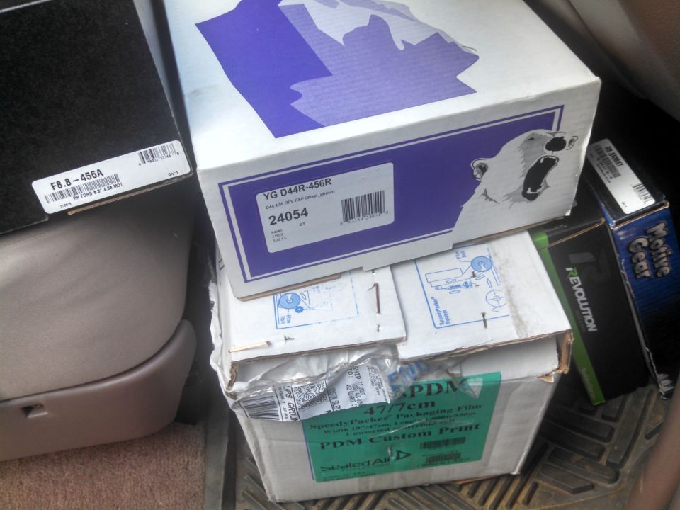 Stacked boxes of gear sets including Yukon YG D44R-456R and Ford 8.8 4.56 ring and pinion inside a vehicle