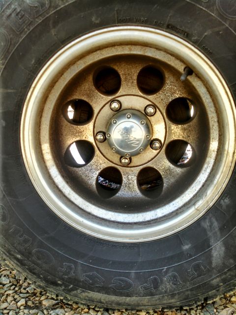 1995 Ford Bronco - A close-up view of a weathered wheel and tire, showing signs of rust and oxidation.
