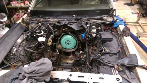 1990 Ford Crown Victoria LTD - The engine bay of a vehicle is shown with the transmission removed, revealing complex wiring and engine parts.