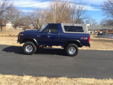 1982 Ford Bronco - This blue 1982 Ford Bronco features a soft top and FX4 Off Road badging, indicating its off-road capabilities.