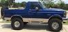 1996 Ford Bronco - This blue Ford Bronco is parked outdoors on a sunny day, showing its side profile and lifted suspension.