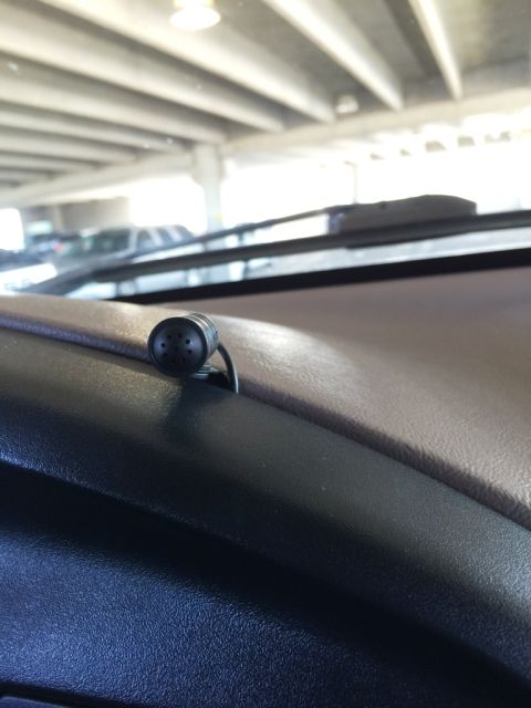 1996 Ford Bronco - A small microphone is attached to the dashboard of a vehicle, with a parking garage visible through the windshield.