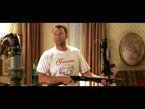 1995 Mercury Grand Marquis - Movie still of a man in a white Ferrara T-shirt holding a pump-action shotgun in a curtained room.