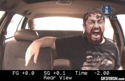 1995 Mercury Grand Marquis - A man with a beard and a black t-shirt is screaming in the back seat of a car, with his arm resting on the headrest. The image appears to b…