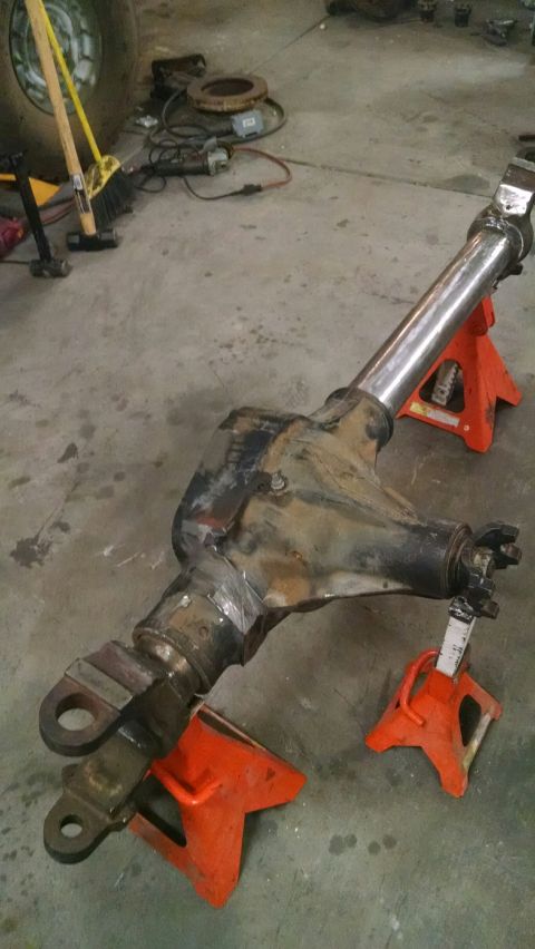 1979 Ford Bronco - A modified front axle assembly, likely for a 1979 Ford Bronco, is supported by orange jack stands on a concrete floor. The axle shows signs…
