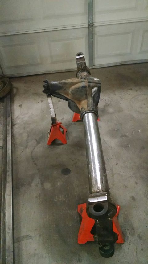 1979 Ford Bronco - A rear axle assembly, likely from a 1979 Ford Bronco, is supported by two orange jack stands on a concrete floor in front of a garage door.…