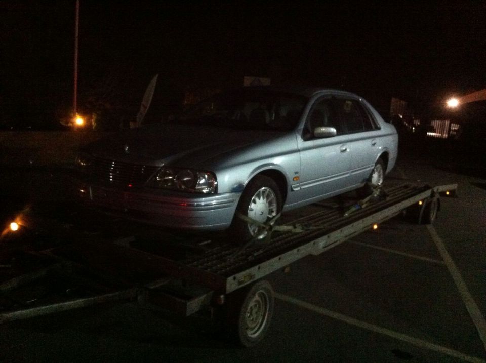 Silver sedan on a car trailer at night