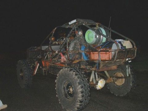 1978 Ford Bronco - A custom-built off-road buggy with a prominent roll cage and large tires is seen from the rear at night.