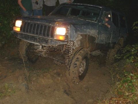 1978 Ford Bronco - Muddy Jeep Cherokee XJ navigating a difficult off-road path.