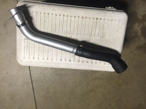 1982 Ford Bronco - A silver metal pipe with a black rubber hose attached is laid across a white Igloo cooler. The cooler has measurement markings on its surfa…