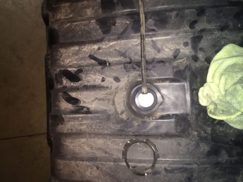 1982 Ford Bronco - A close-up view of the underside of a black plastic fuel tank, possibly from a 1982 Ford Bronco, showing a fuel line entering a grommet and…