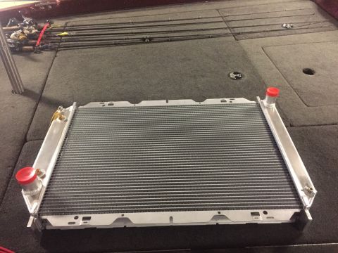 1982 Ford Bronco - A new aluminum radiator with red caps is displayed on the carpeted deck of a boat, with fishing rods in the background.