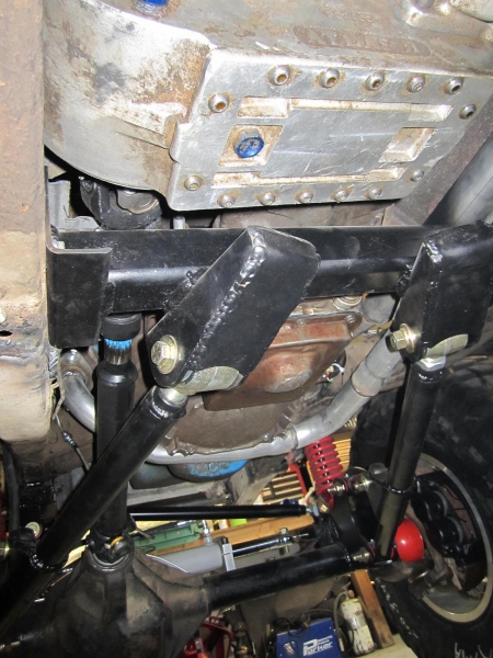 1981 Ford Bronco - Underside view of a modified 1981 Ford Bronco showing a custom suspension setup with black control arms, red shocks, and a differential.
