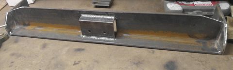 1991 Ford Bronco - A custom-fabricated steel bumper or skid plate with a central bracket featuring two bolt holes is shown lying on a concrete floor. The meta…