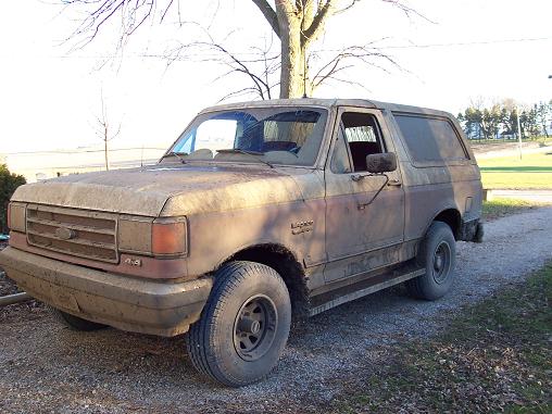 Mud-covered 1987 Ford Bronco parked on a gravel driveway