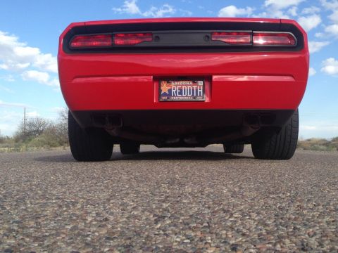 2010 Dodge Challenger - The rear of a red Dodge Challenger is shown parked on a road with a blue sky overhead.