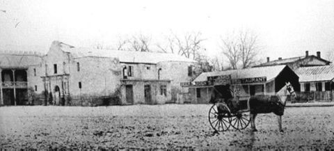 1909 Ford Model T - A horse-drawn carriage is parked in front of historic buildings, one of which appears to be a restaurant.