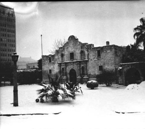 1909 Ford Model T - The historic Alamo mission is blanketed in snow, with a tall building and a lamppost visible in the winter scene.